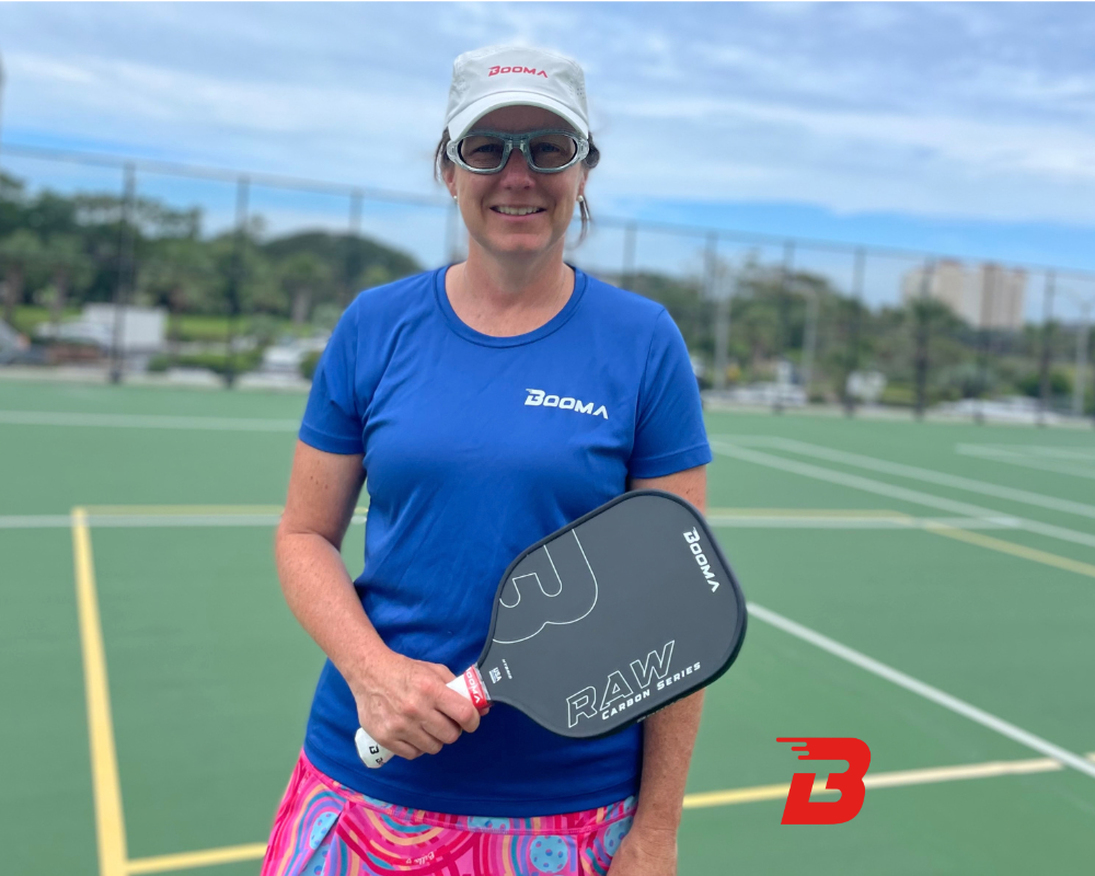 Joueuse de pickleball avec une raquette de pickleball BOOMA Raw Carbon Series dans les mains.