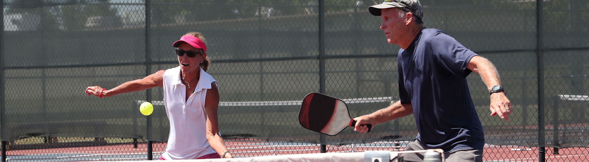 Couple playing pickleball at the net.