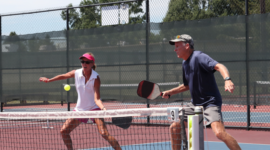 Couple playing pickleball at the net.