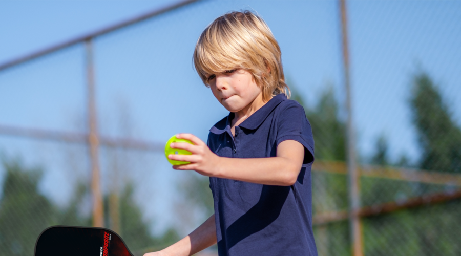 Child playing pickleball getting ready to serve with a BOOMA paddle.