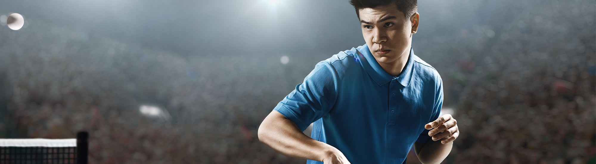 Young ping pong player demonstrating a skilled backhand stroke with focus and intensity.