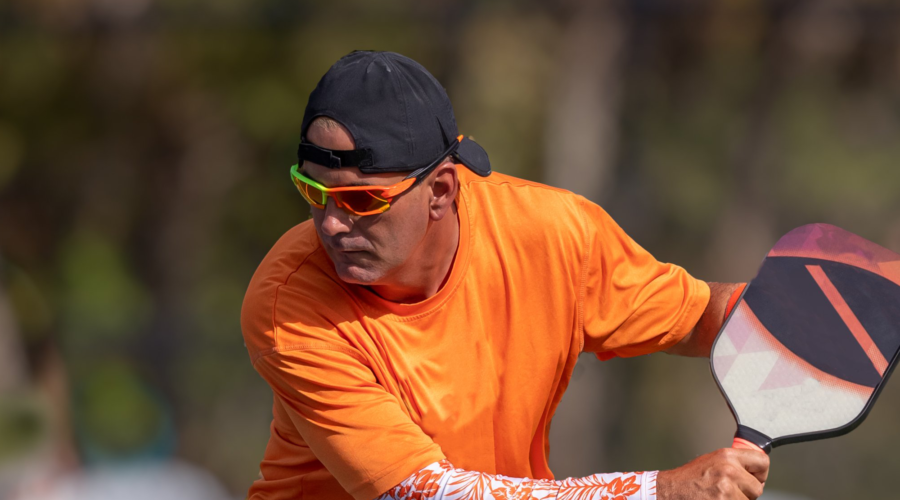 Man with a pickleball paddle hitting a ball.