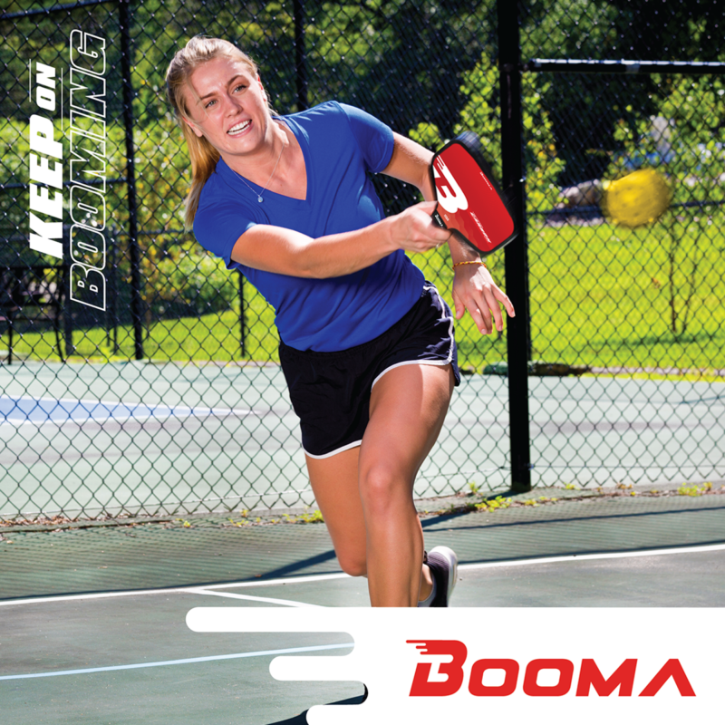 Woman finishing her swing from the back of the court with a BOOMA pickleball paddle.