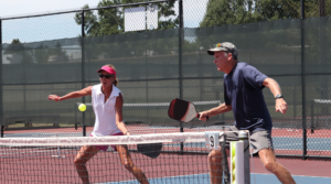 Health and fitness: man and women playing pickleball outdoors looking . 