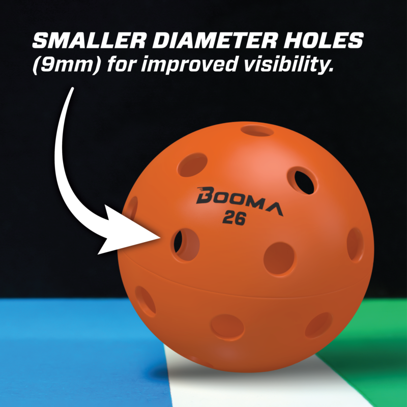 Close-up of an orange BOOMA 26 indoor pickleball ball with an arrow hightlighting the smaller holes.