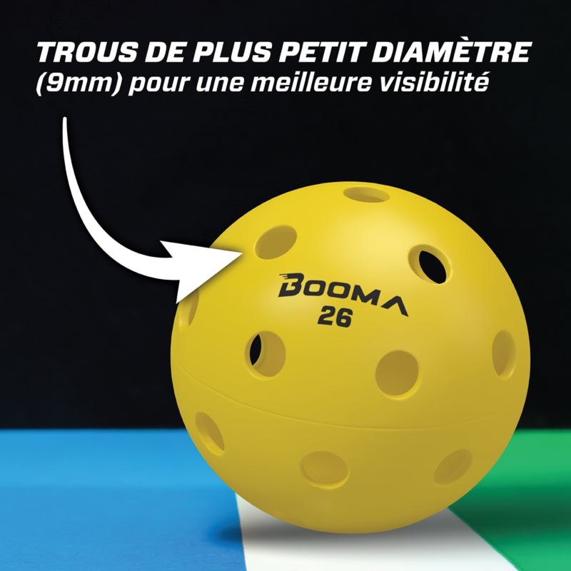 Gros plan d'une balle de pickleball intérieure BOOMA 26 jaune avec une flèche mettant en évidence les petits trous.