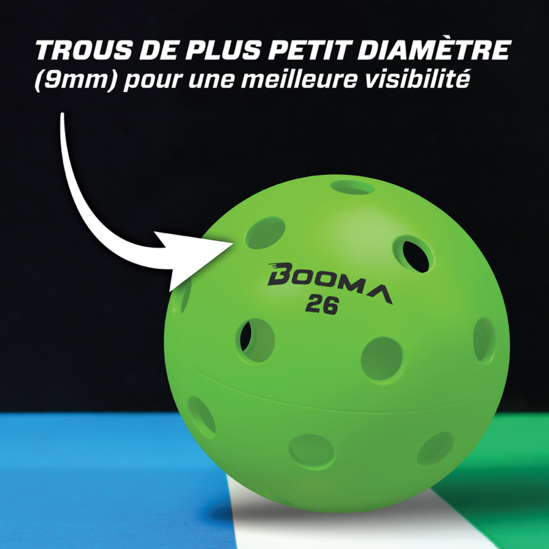 Gros plan d'une balle de pickleball intérieure BOOMA 26 verte avec une flèche mettant en évidence les petits trous.